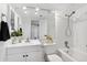 Bright bathroom featuring a shower and tub combination, white tile and fixtures, and a decorative mirror at 8500 E Jefferson Ave # 16B, Denver, CO 80237