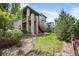Exterior view of green home and backyard with landscaping, staircase to the upper deck and stone pillars at 4421 Tanager Trl, Broomfield, CO 80023