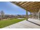 Beautiful backyard with green lawn, stone pillars, and wooden beam patio cover; perfect for outdoor living at 9559 Yucca Way, Arvada, CO 80007