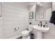 Modern powder room with unique wave-patterned wallpaper, pedestal sink, and sleek fixtures at 9559 Yucca Way, Arvada, CO 80007