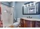 Charming bathroom featuring tiled shower, toilet, and wooden vanity with a granite countertop and decorative mirror at 9239 Erminedale Dr, Lone Tree, CO 80124