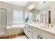 Bright bathroom featuring double sinks, a soaking tub, and a shower with glass doors at 6070 Long Branch Dr, Parker, CO 80134