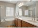 Bright bathroom featuring double sinks, a large mirror, separate shower, and a soaking tub at 6070 Long Branch Dr, Parker, CO 80134