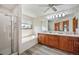 Bright bathroom featuring a bathtub with tiled backsplash, a shower, and a double vanity with wood cabinets at 7900 E Dartmouth Ave # 75, Denver, CO 80231