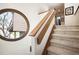 Carpeted staircase with a wood railing and a large round window, providing natural light at 7900 E Dartmouth Ave # 75, Denver, CO 80231