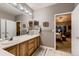 Bathroom with double vanity, wooden cabinets, large mirror, and doorway leading into the bedroom at 20510 Oakbrook Ln, Parker, CO 80138