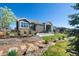 Beautifully landscaped backyard featuring a stone patio, fire pit, and lush greenery at 32 Latigo Pl, Littleton, CO 80123