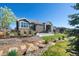 The backyard features a stone patio, built in fire pit, lush grass, and mature landscaping at 32 Latigo Pl, Littleton, CO 80123