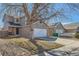 View of a two-story home with a two-car garage, situated in a neighborhood with mature trees at 12144 Newport Dr, Brighton, CO 80602