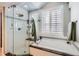 Bright bathroom featuring soaking tub, glass shower, and shuttered windows at 1145 S Logan St, Denver, CO 80210