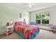 Bright bedroom with a colorful bed, playful decor, and a large window overlooking lush trees at 13235 Clermont Cir, Thornton, CO 80241