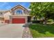 Traditional two-story home featuring well-maintained landscaping, a red garage door, and mature tree at 13235 Clermont Cir, Thornton, CO 80241