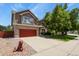 Lovely two-story house with a red garage door, mature tree, and decorative rock landscaping at 13235 Clermont Cir, Thornton, CO 80241