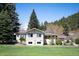 A bright exterior view of a single-story home with a spacious lawn and mature trees at 10049 S Turkey Creek Rd, Morrison, CO 80465