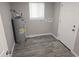 A utility space with gray wood-look flooring, a water heater, and a window at 4720 Thompson Ct, Denver, CO 80216