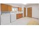 Functional laundry room features appliances, storage cabinets, neutral tile floor, and a window at 55 Dexter St, Denver, CO 80220