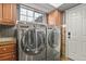 Well-equipped laundry room with stainless steel washer and dryer, cabinets, and ample natural light at 7243 S Kellerman Way, Aurora, CO 80016