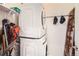 Efficient laundry room featuring stacked washer and dryer units with hooks and overhead shelving for storage at 5676 Emporia St, Denver, CO 80238