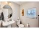 This powder room features a pedestal sink, toilet, window, and tasteful decor for a clean and inviting space at 5676 Emporia St, Denver, CO 80238