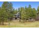 Home exterior featuring stone facade, upper and lower decks, and mature trees at 7317 Fremont Pl, Larkspur, CO 80118