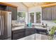 Bright corner kitchen with gray cabinets, stainless steel appliances, and windows showcasing a lush forest view at 7317 Fremont Pl, Larkspur, CO 80118