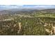 Aerial view of community featuring homes nestled among dense trees, with mountain views in the distance at 3251 Interlocken Dr, Evergreen, CO 80439
