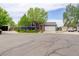 Two-story gray home featuring stone accents, manicured lawn, attached garage, and mature shade trees at 5861 S Orleans Way, Centennial, CO 80015