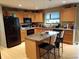 Bright kitchen features granite counters, wood cabinets, a black refrigerator and an island with seating at 5256 E 129Th Pl, Thornton, CO 80241