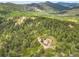 Panoramic aerial view of home on a wooded lot near a mountain with an detached garage at 9648 Yegge Rd, Morrison, CO 80465