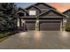 Two-story home featuring a three car garage, dark siding, and manicured landscaping at 6743 Serena Ave, Castle Pines, CO 80108