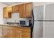 Kitchen featuring wooden cabinets, stainless steel microwave, and a refrigerator at 6743 Serena Ave, Castle Pines, CO 80108