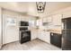 Modern kitchen with white cabinets, black appliances, and wood look floors at 1230 Peoria St, Aurora, CO 80011