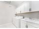 Functional laundry room features white cabinets, a utility sink, washer, and dryer, combining convenience and practicality at 5331 Routt Ct, Arvada, CO 80002