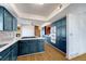 Open kitchen featuring blue cabinets, granite counters, double ovens, and brick alcove at 12925 Sierra Cir, Parker, CO 80138