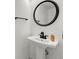 A pedestal sink powder room with a black faucet, round mirror, and black towel bar at 12925 Sierra Cir, Parker, CO 80138
