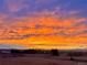 Dramatic sunrise sky with vibrant colors over a landscape featuring a home, trees, and distant mountain views at 12925 Sierra Cir, Parker, CO 80138