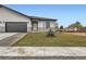 New construction features stucco siding, stone accents, a dark gray garage door, and a small fir tree at 15 S Gray St, Lakewood, CO 80226