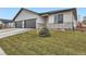 New construction features stucco siding, stone accents, a dark gray garage door, and a small fir tree at 15 S Gray St, Lakewood, CO 80226