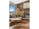 Cozy living room with a striking stone fireplace, wood floors, and view from a large window at 31219 Florence Rd, Conifer, CO 80433