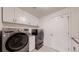 A laundry room showcasing gray modern washer and dryer units and white storage cabinets at 6503 Big Horn Trl, Littleton, CO 80125