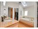 Bright bathroom with a soaking tub under a skylight, a wooden vanity, and a walk-in closet at 27100 Molly Dr, Conifer, CO 80433