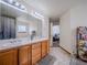Bathroom featuring double sinks, a large mirror, and view to a bedroom through an open doorway at 319 Mountain View Ave, Fort Lupton, CO 80621