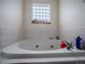 Close-up of a large soaking tub with tile surround and glass block window at 319 Mountain View Ave, Fort Lupton, CO 80621