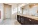 Bright bathroom features double sinks with granite countertops, white cabinets, and tile flooring at 12202 Village Cir, Brighton, CO 80603