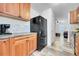 Kitchen features wooden cabinets, tile backsplash, and a sleek black refrigerator at 2791 Quarterland St, Strasburg, CO 80136