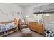 Cozy Bedroom featuring a crib, rocking chair, changing table, and a window for natural light at 2721 W 167Th Pl, Broomfield, CO 80023