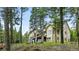 Inviting exterior view of a residence featuring a deck and outdoor seating nestled among the trees at 30041 Marys Dr, Conifer, CO 80433