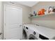 Bright laundry room featuring modern washer and dryer, complemented by a shelf for storage solutions at 4500 Copeland Cir # 104, Highlands Ranch, CO 80126