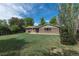 Home's backyard featuring a lush lawn and brick exterior, set against a backdrop of mature trees and blue sky at 2120 S Ouray St, Aurora, CO 80013