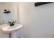 Stylish powder room with a pedestal sink, floating shelves, and neutral tones for a modern aesthetic at 10136 Worchester St, Commerce City, CO 80022